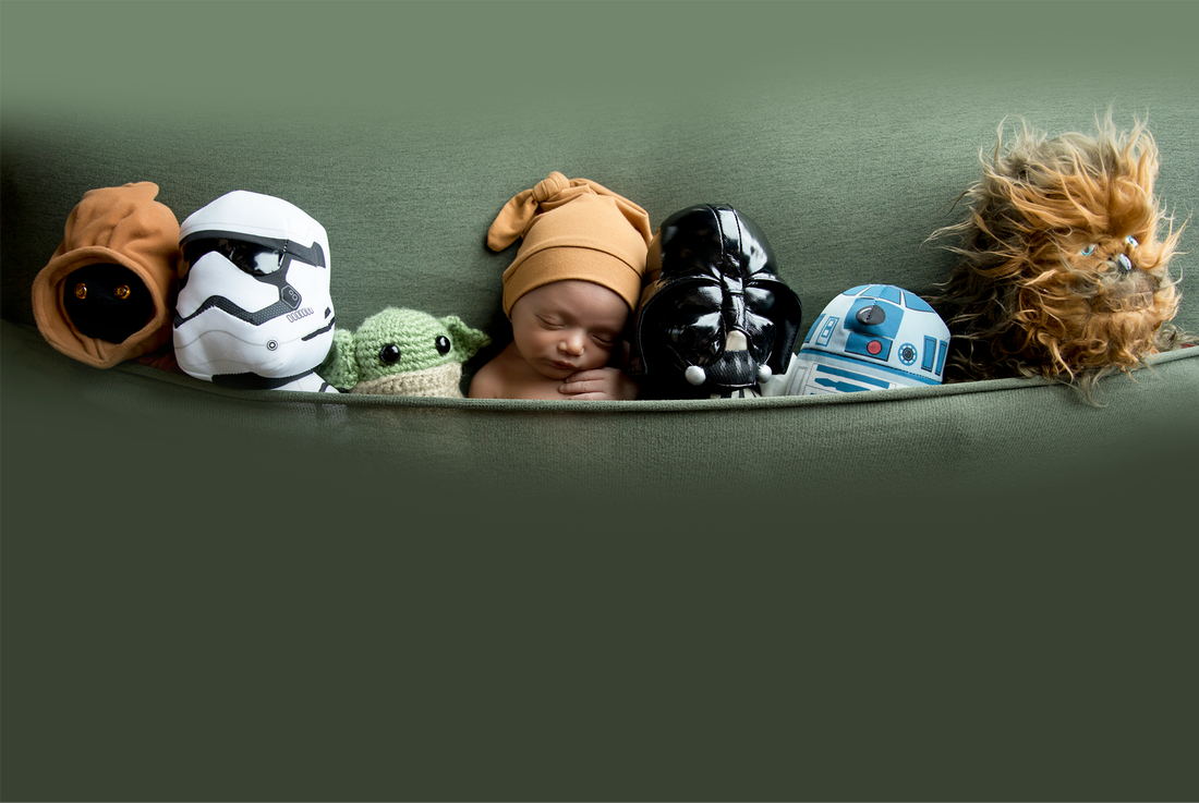Sleeping baby laying on green background with Star Wars plush animals.Picture