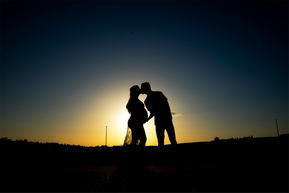 Silhouettes of man and pregnant woman against a blue sky and sunset