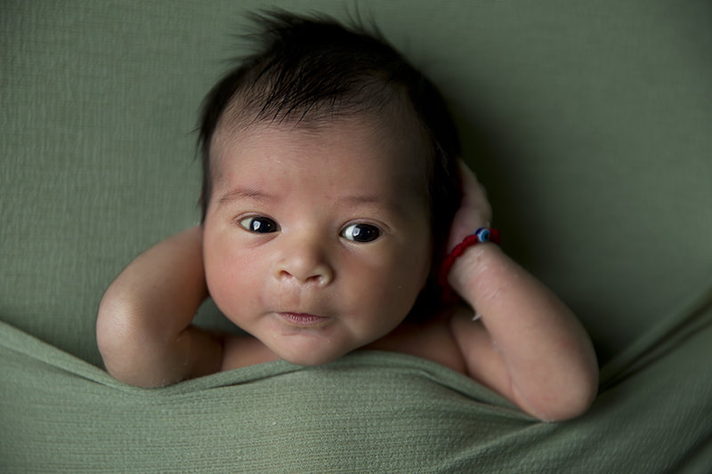 Baby laying on green background.